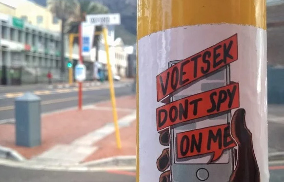 A sticker on a streetpole that says 'Voetsek don't spy on me'